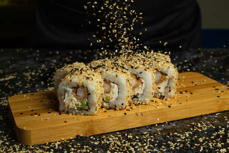 Traditional delicious fresh sushi roll set on a black background with reflection. Sushi roll with rice, cream cheese, avocado, salmon, sesame. Philadelphia. Sushi menu. Japanese kitchen, restaurant.の写真素材