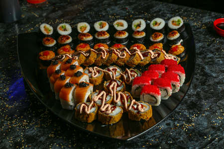 Traditional delicious fresh sushi roll set on a black background with reflection. Sushi roll with rice, red fish, salmon. Sushi menu. Japanese kitchen, restaurant. Seafood, asian foodの写真素材