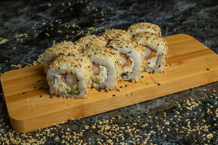 Traditional delicious fresh sushi roll set on a black background with reflection. Sushi roll with rice, cream cheese, avocado, salmon, sesame. Philadelphia. Sushi menu. Japanese kitchen, restaurant.の写真素材