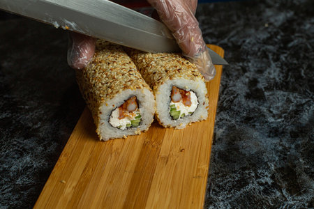 Traditional delicious fresh sushi roll set on a black background with reflection. Sushi roll with rice, cream cheese, avocado, salmon, sesame. Philadelphia. Sushi menu. Japanese kitchen, restaurant.の写真素材