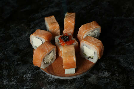 Traditional delicious fresh sushi roll set on a black background with reflection. Sushi roll with rice, red fish, salmon. Sushi menu. Japanese kitchen, restaurant. Seafood, asian foodの写真素材