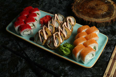 Traditional delicious fresh sushi roll set on a black background with reflection. Sushi roll with rice, red fish, salmon. Sushi menu. Japanese kitchen, restaurant. Seafood, asian foodの写真素材