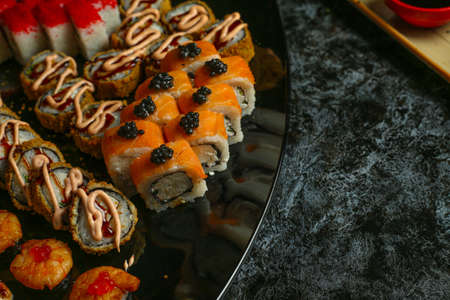 Traditional delicious fresh sushi roll set on a black background with reflection. Sushi roll with rice, red fish, salmon. Sushi menu. Japanese kitchen, restaurant. Seafood, asian foodの写真素材