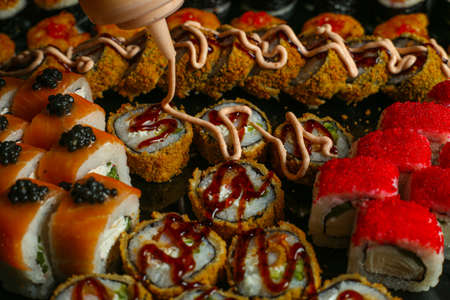 Traditional delicious fresh sushi roll set on a black background with reflection. Sushi roll with rice, red fish, salmon. Sushi menu. Japanese kitchen, restaurant. Seafood, asian foodの写真素材
