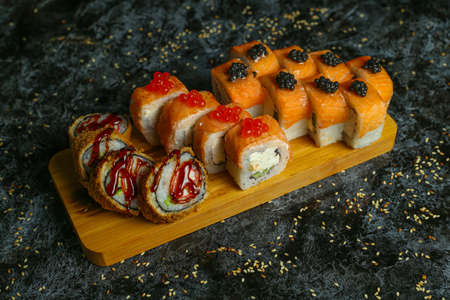 Traditional delicious fresh sushi roll set on a black background with reflection. Sushi roll with rice, red fish, salmon. Sushi menu. Japanese kitchen, restaurant. Seafood, asian foodの写真素材