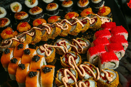 Traditional delicious fresh sushi roll set on a black background with reflection. Sushi roll with rice, red fish, salmon. Sushi menu. Japanese kitchen, restaurant. Seafood, asian foodの写真素材