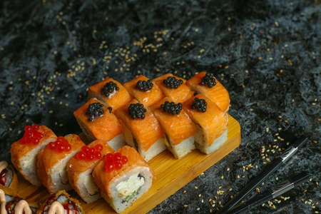 Traditional delicious fresh sushi roll set on a black background with reflection. Sushi roll with rice, red fish, salmon. Sushi menu. Japanese kitchen, restaurant. Seafood, asian foodの写真素材