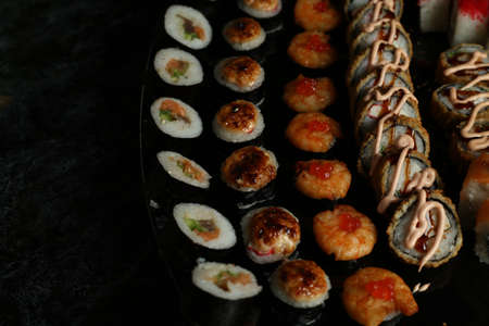 Traditional delicious fresh sushi roll set on a black background with reflection. Sushi roll with rice, red fish, salmon. Sushi menu. Japanese kitchen, restaurant. Seafood, asian foodの写真素材