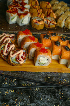 Traditional delicious fresh sushi roll set on a black background with reflection. Sushi roll with rice, red fish, salmon. Sushi menu. Japanese kitchen, restaurant. Seafood, asian foodの写真素材