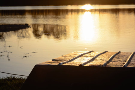 sunset reflecting off a pond with a  boat in the foregroundの写真素材
