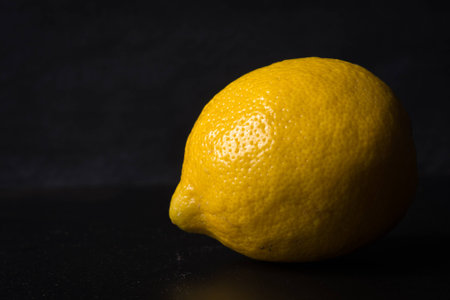 Isolated lemon on dark background side lit showing texture.の写真素材