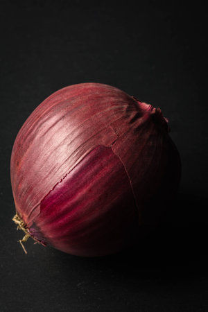 Side lit red onion on a black back groundの写真素材