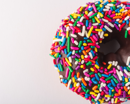 Half doughnut with multicolored sprinkles on a white backgroundの写真素材