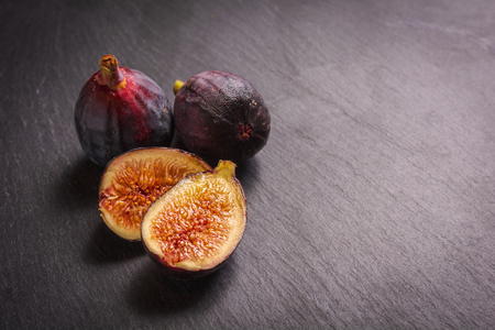 Grouping of figs, one cut open to show texture of the fruit on slate.の写真素材