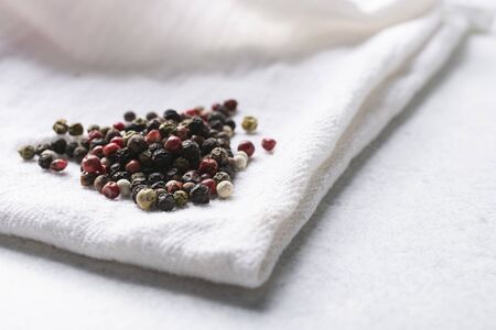 Pile of peppercorns on a white cloth napkin.