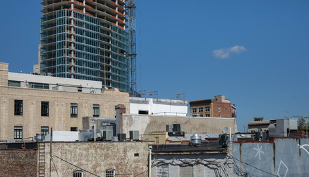 Brand new construction of a high rise building towering over old city buildings.の写真素材