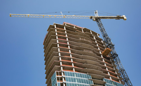 Construction of a new high rise building with a crane and bright blue sky for background.の写真素材