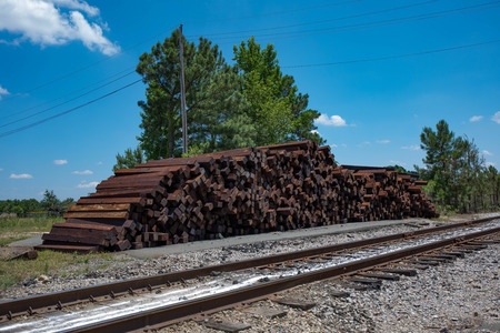 A large pile of unused railroad ties stacked beside the railroad tracks.  (high saturation)の写真素材