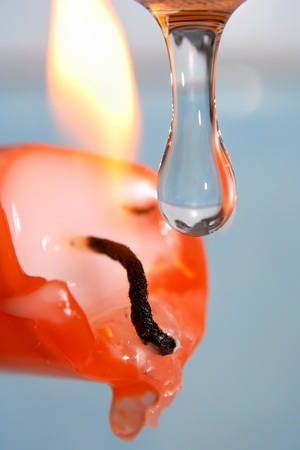 Clear, blue water dropping into candle flame の写真素材