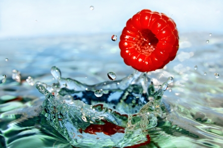 Drops of clear, blue water with and fruits of raspberryの写真素材