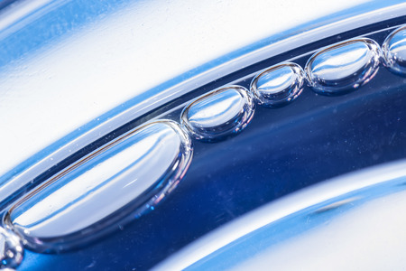 Blue bubbles in clear water against whiteの写真素材