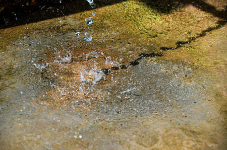 Water splash falling from the cave stone. Water drops scattered and drippingの写真素材