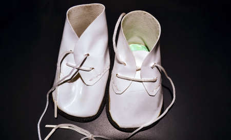 Closeup of a doll shoe in dark background with a flash light. Top directional lighting on a small...