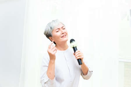 Happy senior asian woman singing with microphone.の写真素材