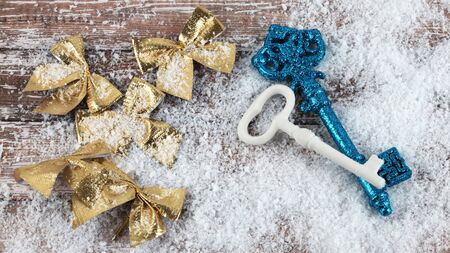 Christmas composition of gold bows and keys on snow covered wooden 
surface. Top viewの写真素材