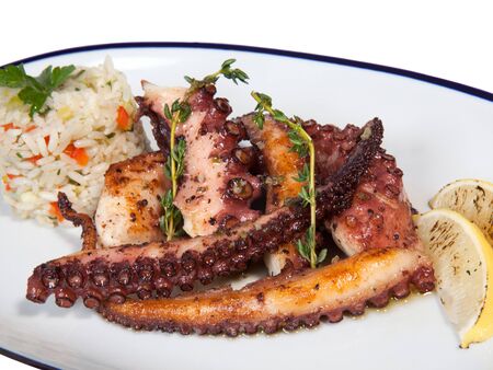 Grilled seafood octopus with rice and lemon on white oval plate with blue edge. Isolated on white background. Close-up photoの写真素材