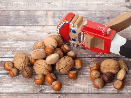 Nutcracker. Wooden Christmas toy with inshell nuts on wooden background. With copy space