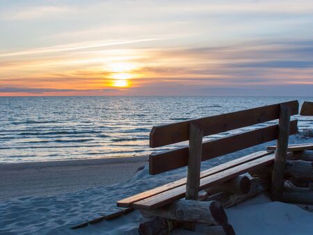 Wooden bench with sunset sea view on the beachの写真素材
