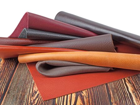 Different colors natural leather textures samples on dark wooden background
