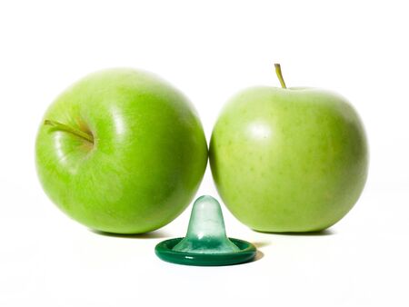 Unwrapped color condom with fruit flavor and green apples on white background. Macro shot. Safe sex conceptの写真素材