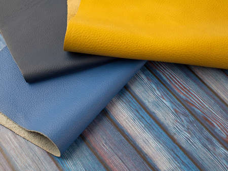 Different colors natural leather textures samples on blue wooden background