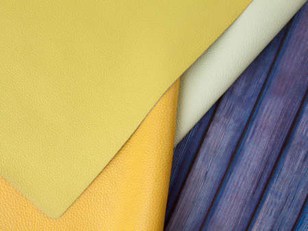 Different colors natural leather textures samples on blue wooden background