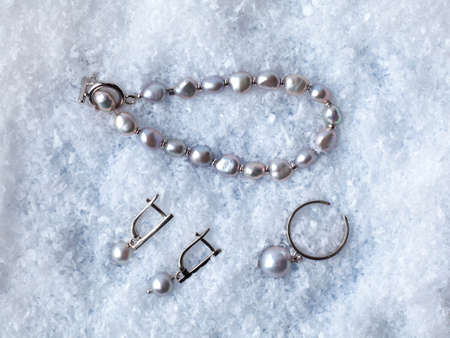 Luxury elegant black baroque pearl earrings, ring and bracelet on white snow background. Close-up shotの写真素材