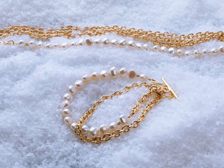 Luxury elegant baroque pearl and golden bracelet and necklace on white snow background. Close-up shotの写真素材