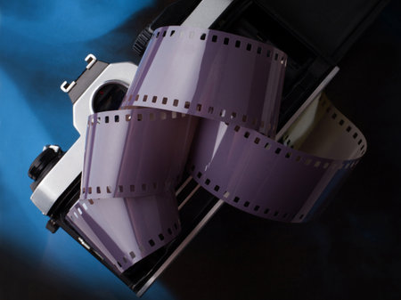 Open vintage old film camera with film strip on gradient blue black backgroundの写真素材