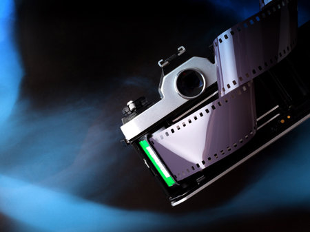 Open old vintage film camera with film strip on abstract gradient blue black background. With copy...