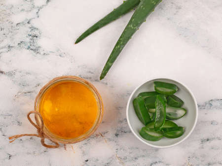 Aloe Vera and honey closeup on light marble background. Sliced Aloe vera natural organic renewal cosmetics, alternative medicine, organic skin care concept. Top view. With copy spaceの写真素材