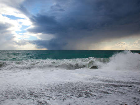 Picturesque turquoise sea with waves and foam and beautiful clouds in the skyの写真素材