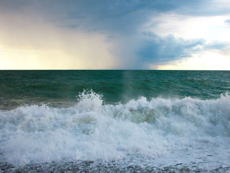 Turquoise sea with waves and foam and beautiful clouds in the skyの写真素材