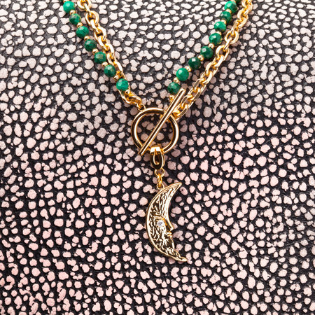Female golden moon shaped pendant with golden chain and green malachite neklace on spotted leather background. Close-up shotの写真素材