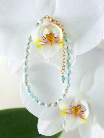 Golden bracelet with turquoise gems on white orchid flowerの写真素材