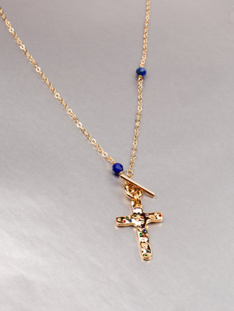 Female cross shaped pendant with golden chain and green malachite neklace on gray background. close up shotの写真素材