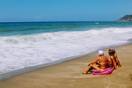July, 2017 - Three tanned women sunbathe on a pink mattress sitting on the seashore at Cleopatra Beach (Alanya, Turkey).のeditorial素材