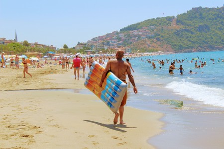 July, 2017 - A man carries an air mattress along the seashore at Cleopatra Beach (Alanya, Turkey).のeditorial素材
