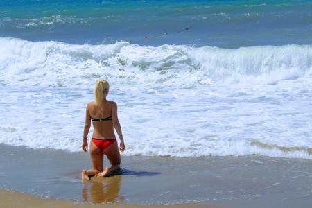 July, 2017 - A woman in a red swimsuit in the surf on the seashore at Cleopatra Beach (Alanya, Turkey).のeditorial素材