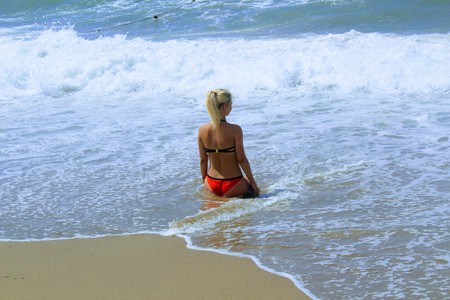 July, 2017 - A woman in a red swimsuit in the surf on the seashore at Cleopatra Beach (Alanya, Turkey).のeditorial素材